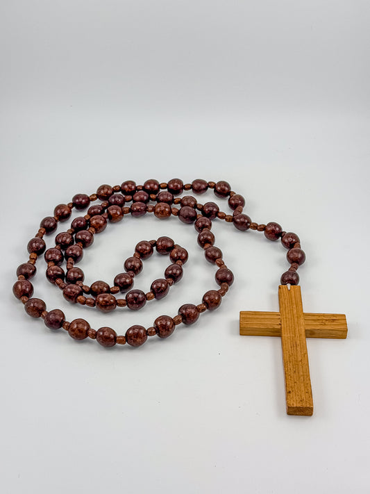 Vintage 40-inch monastic wood bead rosary held in hand showing full length and hand-carved cross pendant