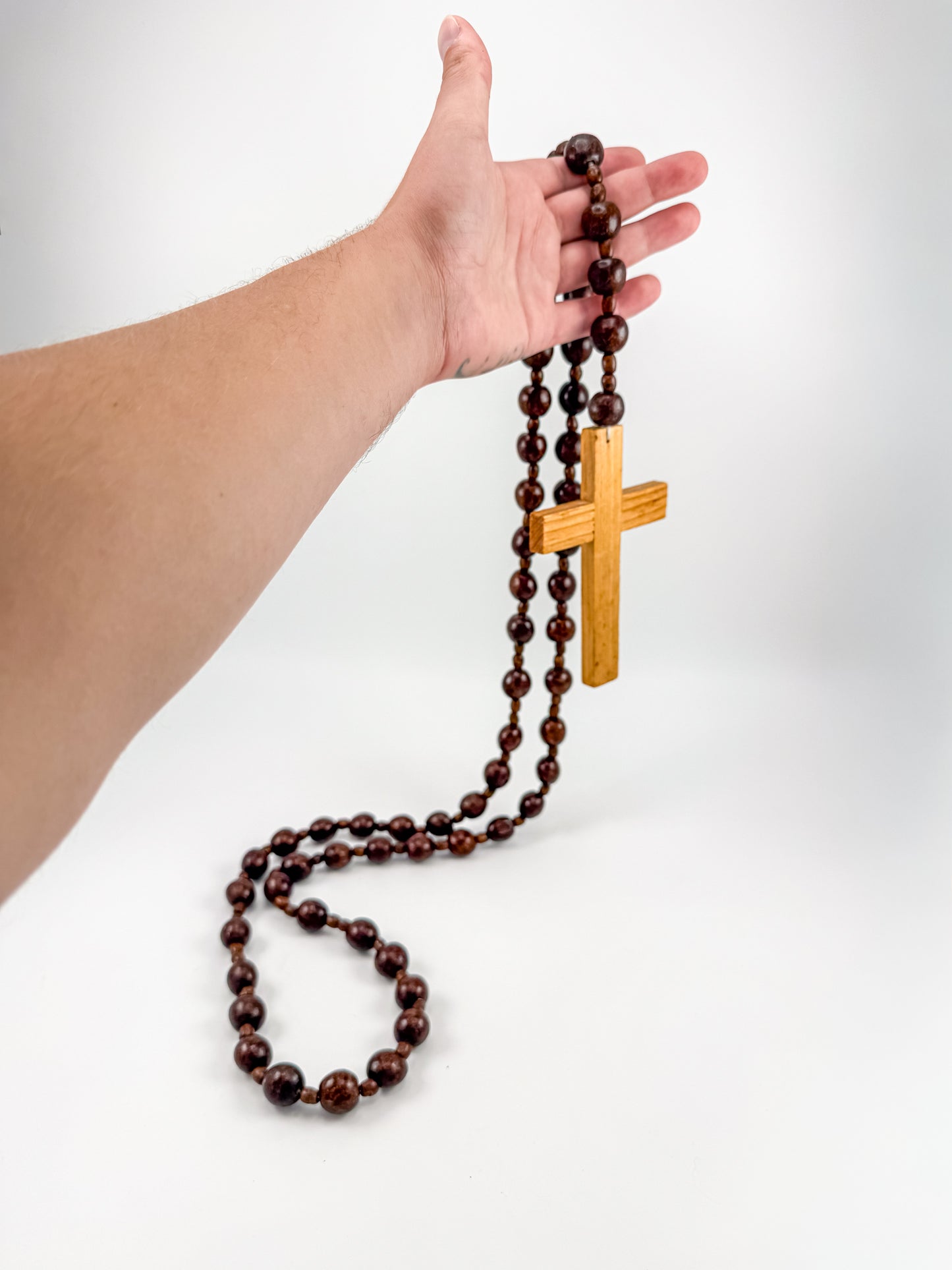 Close-up of hand-carved light wood cross pendant with vertical channel detailing